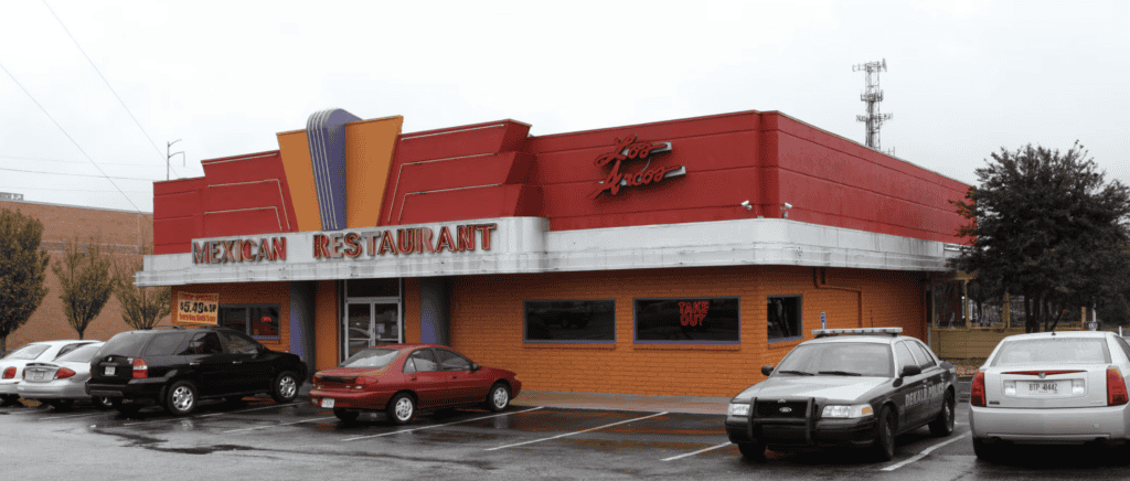 A red and orange Stone Mountain restaurant with a "Take Out" sign sits in a parking lot filled with cars, including a police car.