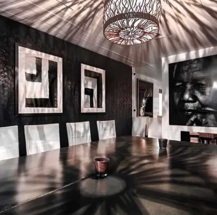 A black and white dining room with a large painting on the wall.
