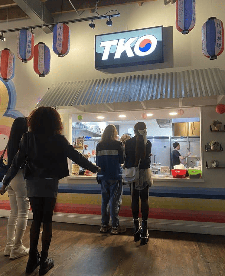 Customers waiting in line at a tko food counter with colorful decorations in East Atlanta Village.