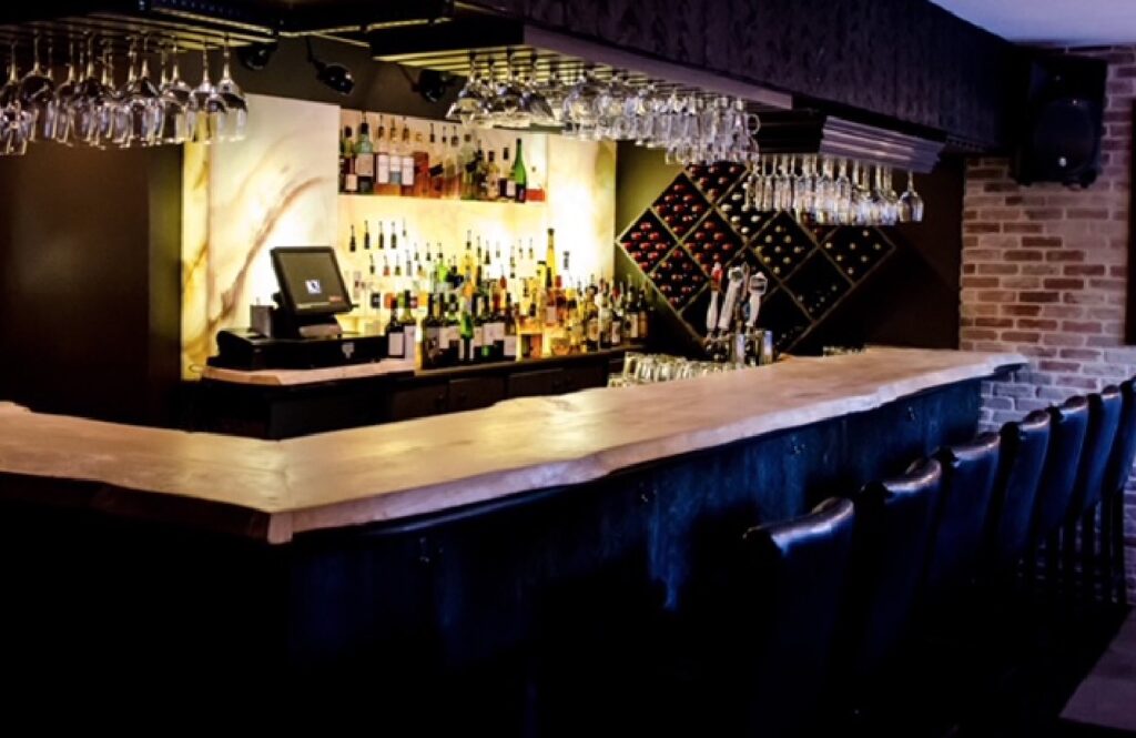 A bar with wine glasses and a brick wall.