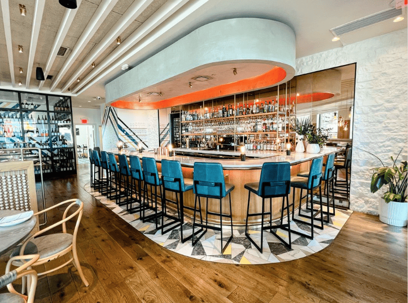 The interior of a restaurant with a bar and chairs.